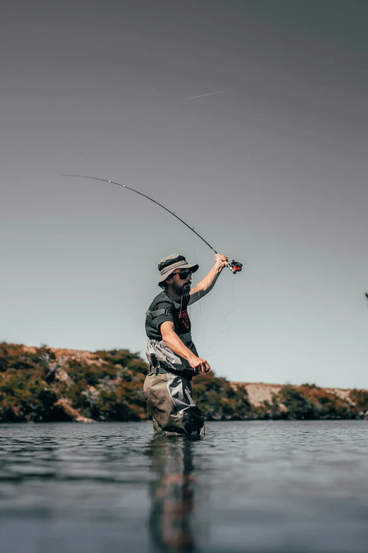 Fly fisherman wading a river and casting