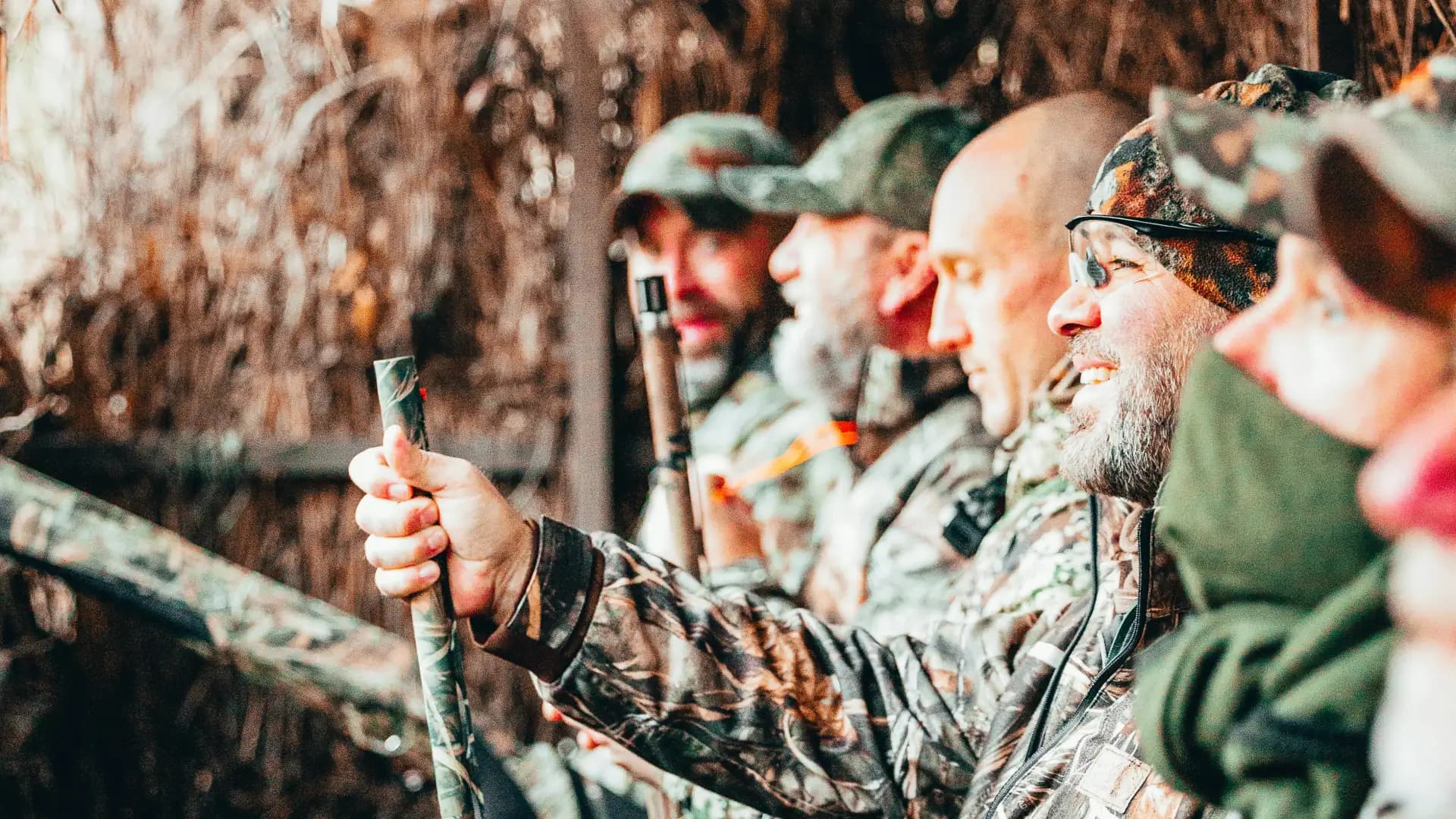 Row of duck hunters in camo watching the sky from a blind