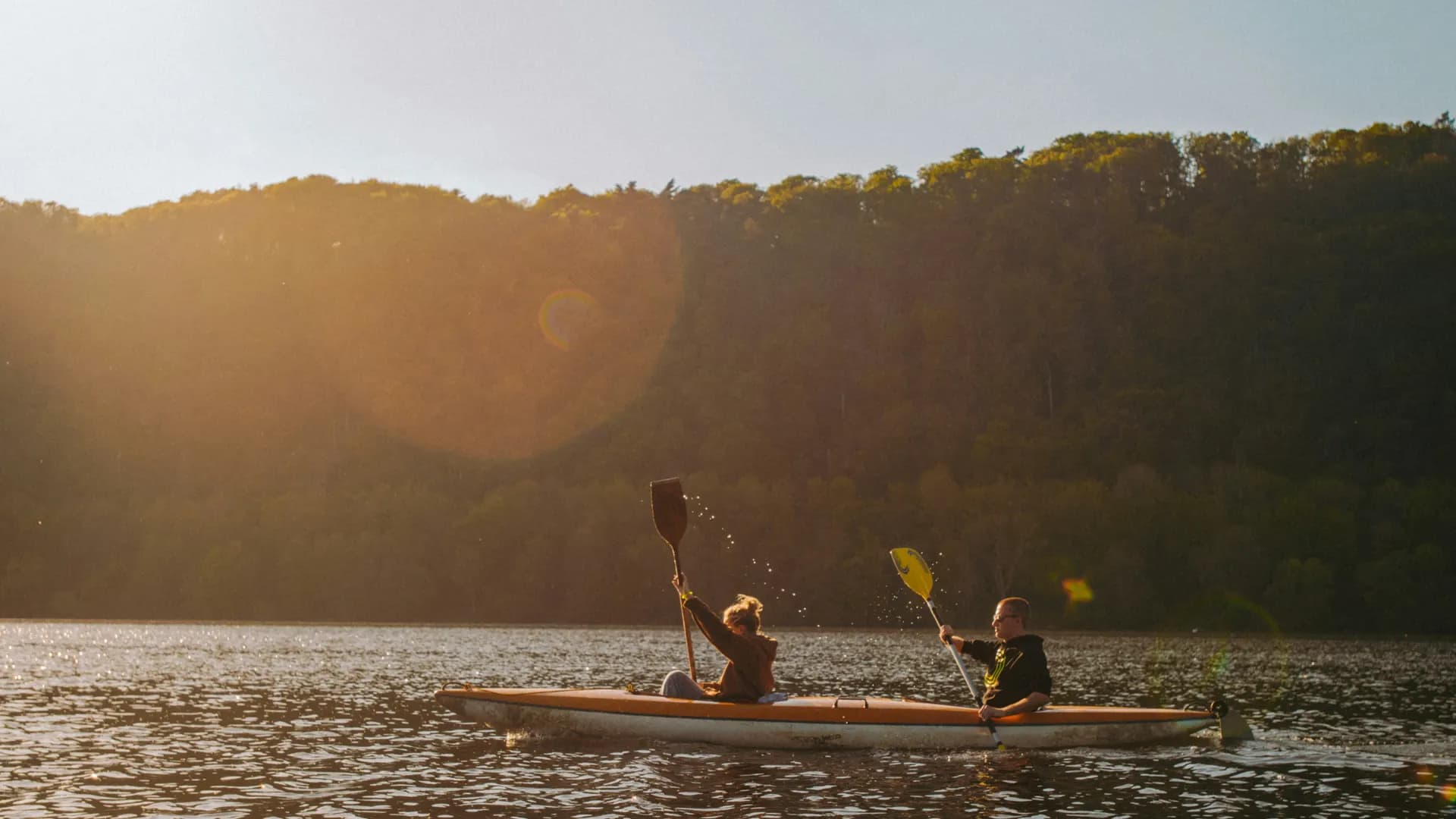 Two kayakers paddling at sunrise