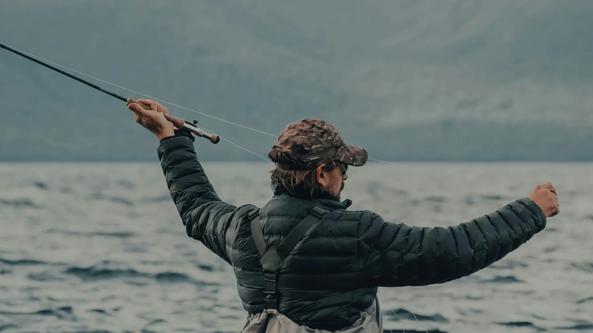 Fly fisherman wading a river at dawn