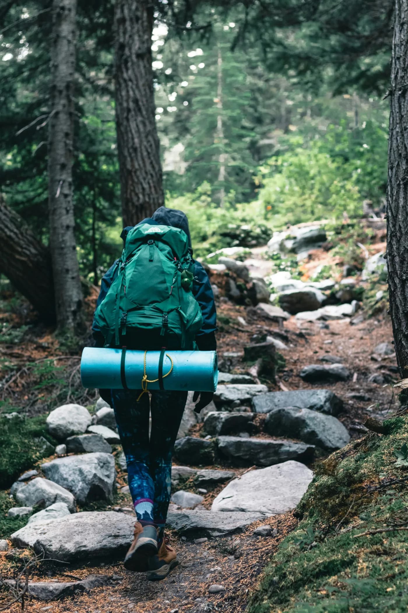 Backpacker on a rocky forest trail