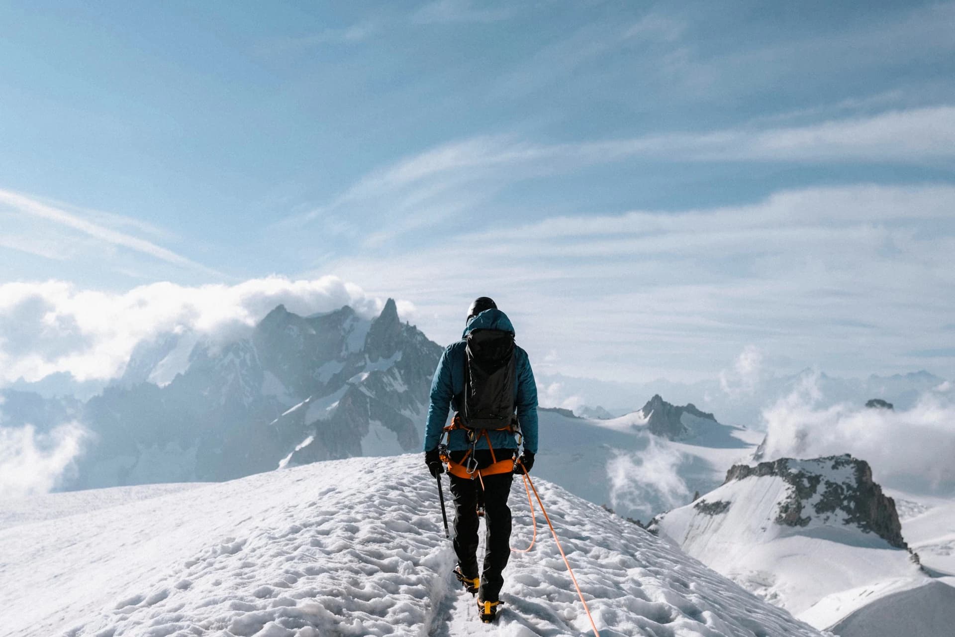 Mountaineer with an ice axe climbing a snowy ridge